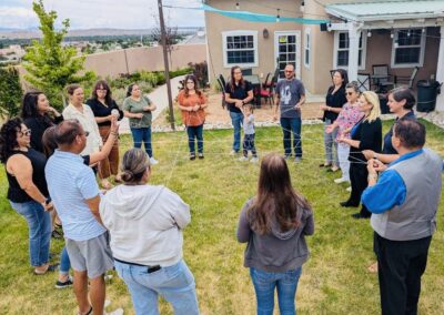 Coalition members stand in a circle outdoors, holding strands of string stretched between them to form a web.